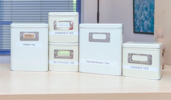 Auf einer Theke stehen verschieden große Teedosen mit unterschiedlichen Teesoerten.