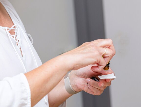 Eine Pflegekraft tropft ätherisches Öl auf einen Tupfer. 