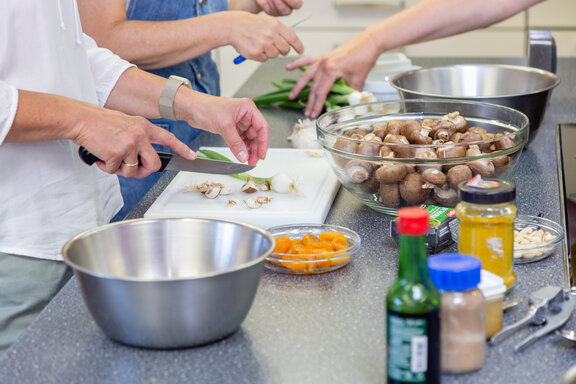 Drei Rehabilitanden stehen in der Küche und schneiden Gemüse klein.