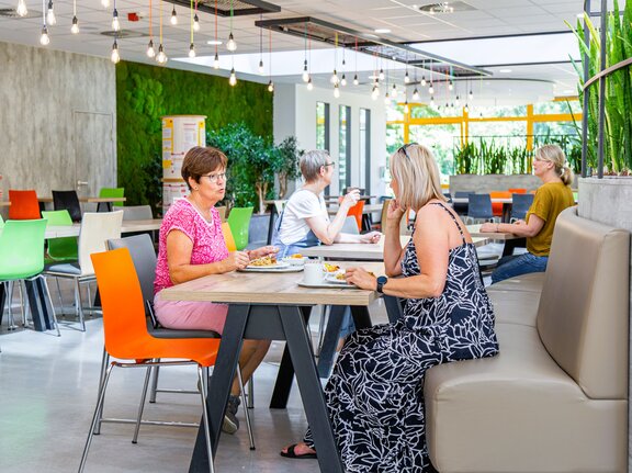 Rehabilitanden sitzen in der Cafeteria und unterhalten sich. 