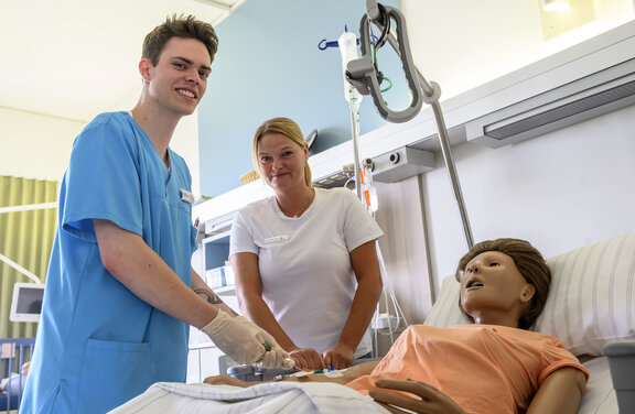 Pflegefachkräfte legen einen Zugang an einem Beispielpatientem 